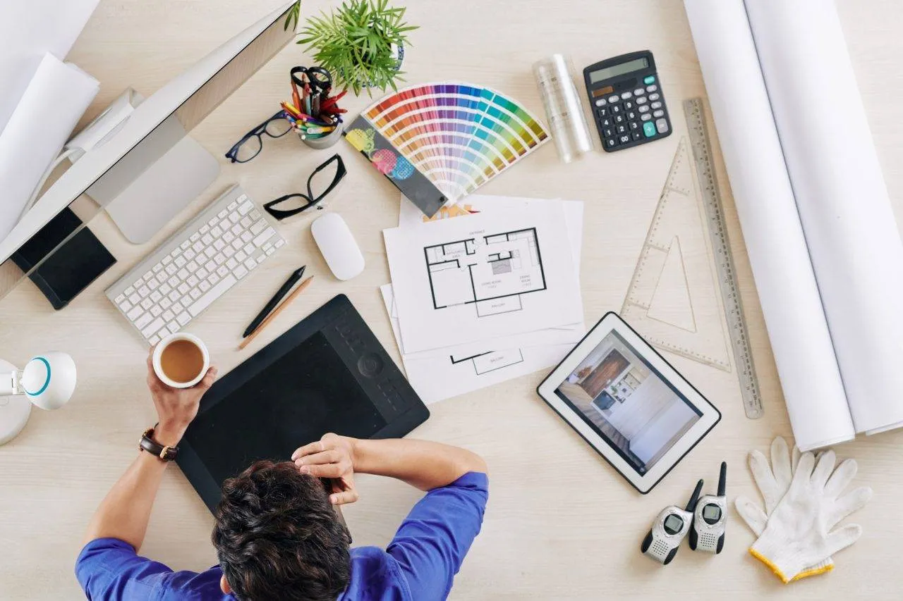 Top view of an interior designer working at a creative desk with color swatches and architectural plans