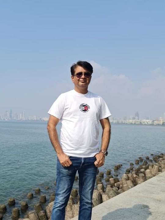 Jeetendra from SK Design Studio standing by the sea with Mumbai skyline in background.